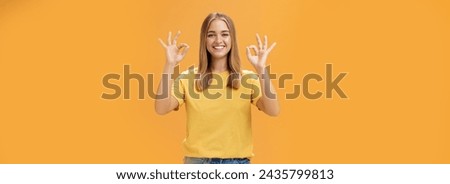 Optimistic charming woman with fair hair and no make-up in yellow t-shirt showing okay or approval gesture assuring everything ok and nothing to worry she can handle project alone, smiling confident