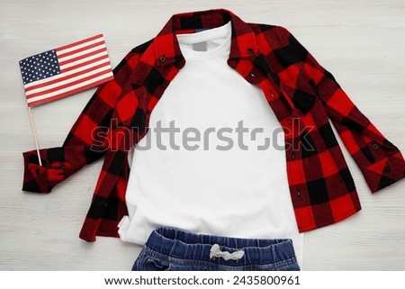 White boy t-shirt mockup, flat lay composition with USA flat, jeans trousers and red plaid shirt. Royalty-Free Stock Photo #2435800961