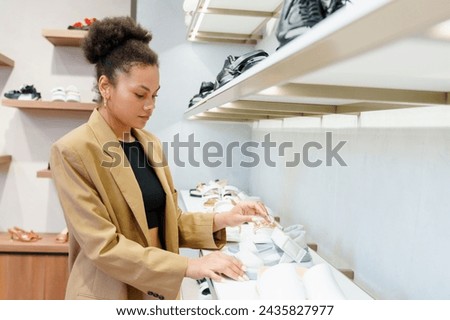African American young woman while choosing shoes while shopping