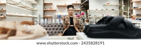 Portrait of an African-American woman who holds stylish high-heeled shoes in her hands in a store.