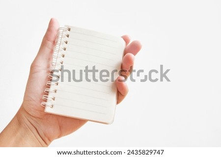 Hand holding blank mini spiral notebook on white background