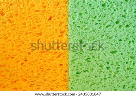 Colorful orange and green dishwashing sponges with pores texture for background graphics. Close-up macro photo of two household sponges tissue. Royalty-Free Stock Photo #2435831847