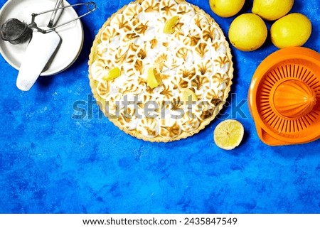 Traditional french lemon Meringue tart with fruits and orange juicer on blue grunge  background