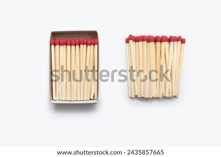 Matches in an open matchbox and many matches near the matchbox isolated on white background. Red matches on a white background are vertically arranged. Top view of matches close-up with space for text Royalty-Free Stock Photo #2435857665