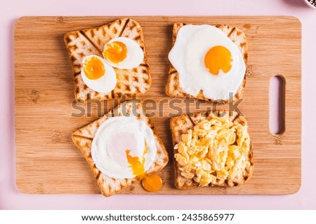 Homemade scrambled egg, poached egg, fried egg, boiled egg on toast on a board top view Royalty-Free Stock Photo #2435865977