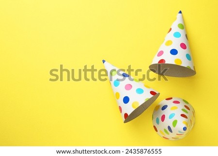 Beautiful party hats on yellow background, top view. Space for text