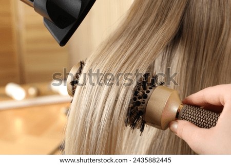 Hairdresser blow drying client's hair in salon, closeup Royalty-Free Stock Photo #2435882445