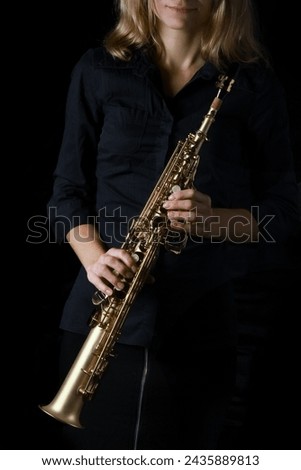 soprano saxophone in hands on a black background Royalty-Free Stock Photo #2435889813
