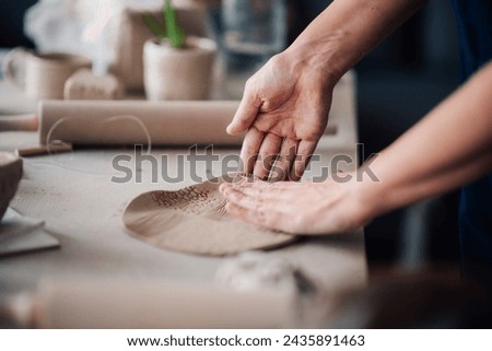 Cropped picture of creative craftswoman's hands shaping wet clay on pottery class in modern workshop. Close up of ceramist's hands shaping wet clay and making contemporary earthenware and handcrafts.