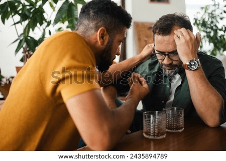 Best friends, supporting each other, drinking whiskey and talking. Discussing problems and drowning sorrows in alcohol. Concept of male friendship, bromance. Royalty-Free Stock Photo #2435894789