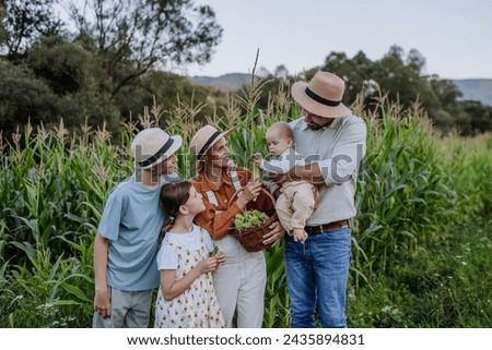 Farmer family standign in front of field with corn. Concept of multigenerational and family farming.