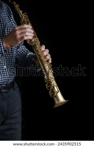 soprano saxophone in hands on a black background Royalty-Free Stock Photo #2435902515