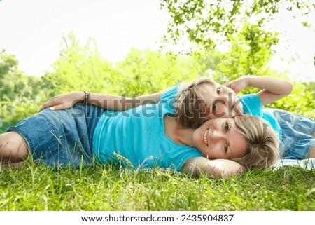child with mother play outdoors in a park on the mother in the grass