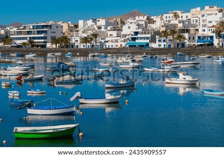 Arrecife Spain scenic photographs of boats in the harbor ancient roman viaduct and bridge made of stones bright blue sky with clouds white wall with green doors vintage fiat man standing against wall