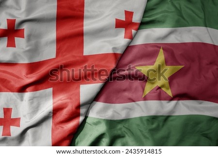 big waving national colorful flag of suriname and national flag of georgia . macro