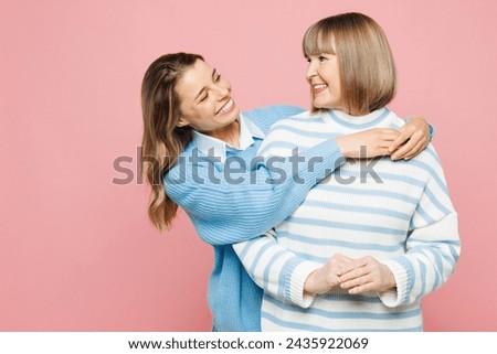 Elder cheerful parent mom 50s years old with young adult daughter two women together wear blue casual clothes hug look to each other isolated on plain pastel light pink background. Family day concept