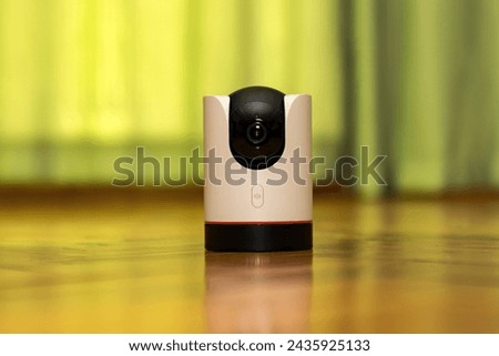 CCTV camera operating in home. Surveillance camera to protect and monitor your home through a mobile application. Home Security System Concept. smart camera on wooden table. 360 degrees rotating head Royalty-Free Stock Photo #2435925133