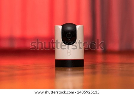 CCTV camera operating in home. Surveillance camera to protect and monitor your home through a mobile application. Home Security System Concept. smart camera on wooden table. 360 degrees rotating head Royalty-Free Stock Photo #2435925135