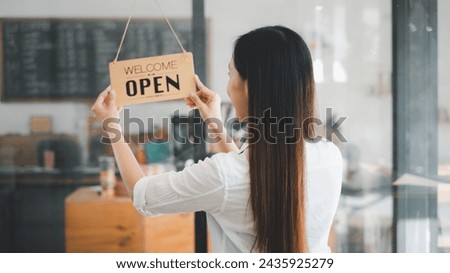 Young entrepreneur holding open sign on glass door at cafe