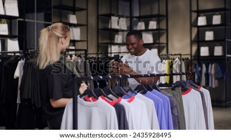 A man photographs his beloved in a clothing store while shopping, she asked him to photograph her in a new look while shopping, in this picture man and woman are choosing a new wardrobe and shopping.