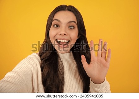 Trendy beautiful teenage model making selfie posing on yellow studio background. Teen fashion. Happy face, positive and smiling emotions of teenager girl.