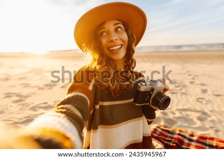 Pretty woman with a professional photographer taking selfie on the beach at sunset. Travel blog.  Adventure, vacation concept.
