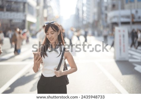 Tokyo smiles, joyful woman in Tokyo, using her smartphone amidst the bustling urban environment.