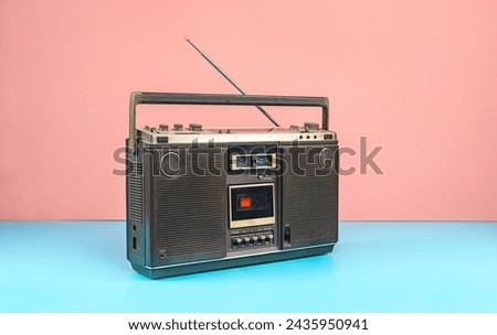 Retro outdated portable stereo boombox radio cassette recorder on colorful background, vintage old cassette radio with antenna on mint blue floor.