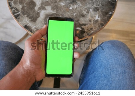 Close up of young man hand using smart phone with green screen 