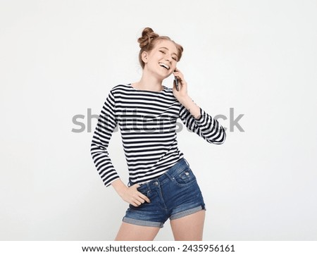 Young smiling blond woman with buns hair hearing exciting news on smartphone over white background