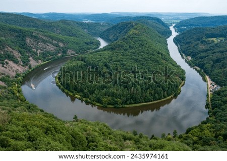 Majestic view of Saar River flowing through the famous Saarschleife in western Germany, surrounded by lush green forest Royalty-Free Stock Photo #2435974161