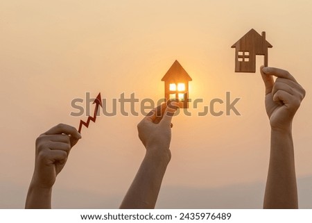 silhouette hands holding small wooden house and arrow against sunset. real estate to growth and legal wealth, copy space
