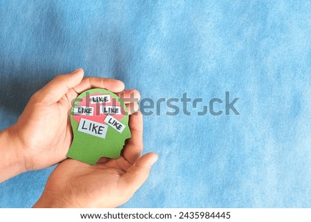 Social media addiction, mental health and belongingness concept. Human hand holding a head profile with word like. Royalty-Free Stock Photo #2435984445