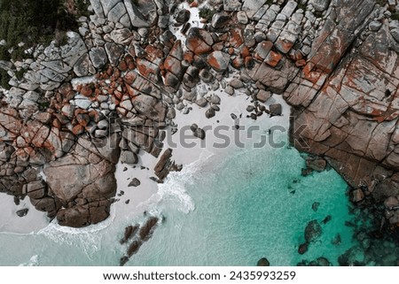 Aerial view of the Bay of fires in Tasmania. Beautiful coastline with orange rocks, white sand and transparent blue water. Drone footage in Australia.