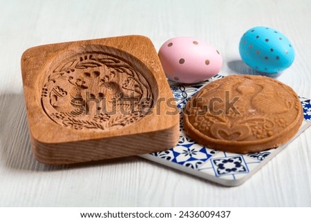 Homemade printed gingerbread in the shape of an Easter egg and a wooden gingerbread mold in close-up. Royalty-Free Stock Photo #2436009437