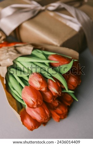 Bouquet of red tulips and a gift box with a bow, festive concept.