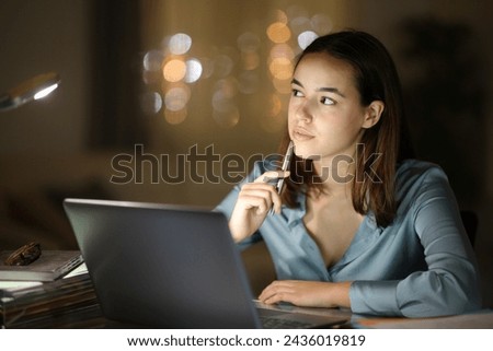Serious tele worker in the night thinking looking at side and working at home Royalty-Free Stock Photo #2436019819