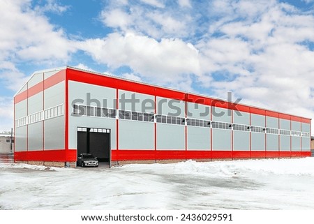 Modern grey-red industrial warehouse distribution building against a blue sky background