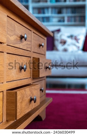 Wooden cabinet of small drawers  in a lounge setting with metal pull knobs. Stylish traditional home storage furniture. Home living  interiors design. Focus in the foreground. 