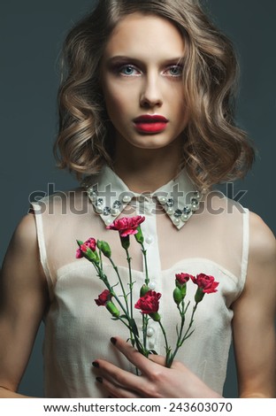 Woman beauty. Portrait ot young gorgeous glamour woman with blue eyes, red lips, flowers over grey background. Perfect make up and hair style. Close up.