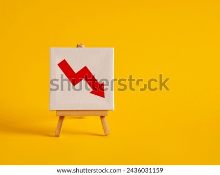 A canvas with decreasing graph symbol on an easel with yellow background with copy space. decreasing sales or profit. Business crisis, economic crash or recession. Falling stock prices.