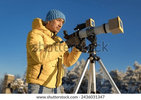 Amateur astronomer looking at the Sun trough a telescope with special solar filter. Royalty-Free Stock Photo #2436031347