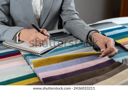 female hand selects the color fabric catalog she likes for new sofa. Textile industry background