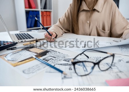Young woman designer working with house sketch plan blue print in the office. Workplace, industry concept