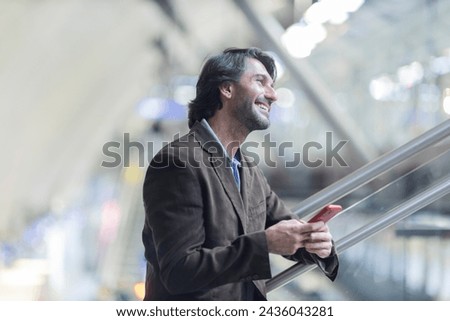 View of young man using a smartphone inside a subway - metro station with a blurred view landscape in the background. High quality photo.