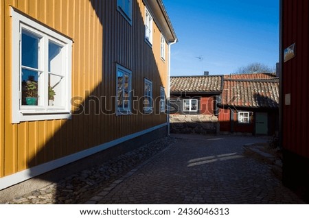 Cozy street with small colorful residential buildings in the old town of Västerås on a sunny day in early spring, wooden red and yellow traditional Scandinavian houses Royalty-Free Stock Photo #2436046313