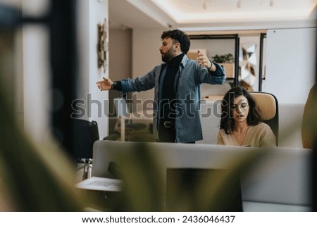 Frustrated by his coworkers letdown, he raises his arms, irritated by the repetition of the same error by his team. Royalty-Free Stock Photo #2436046437