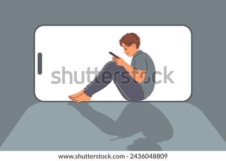 Boy suffers from digital addiction and uncontrollably uses mobile phone to chat on social networks. Child with cyber addiction dreams of becoming blogger so can work through phone. Royalty-Free Stock Photo #2436048809