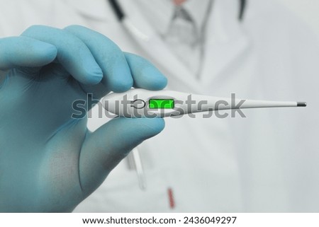 Electronic thermometer in the hands of a doctor, close-up. Chromakey. Copy space. Doctor in medical gloves
