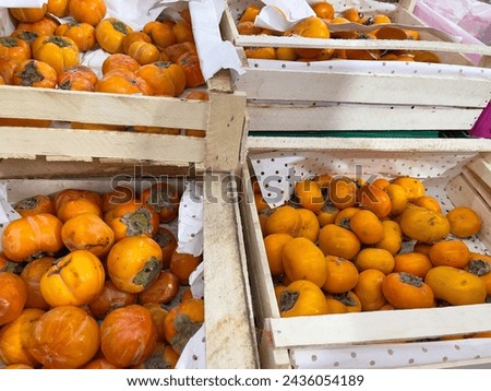 Ripe persimmon fruit in wooden boxes at the market.